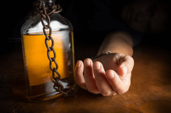 Hand chained to glass bottle of alcohol