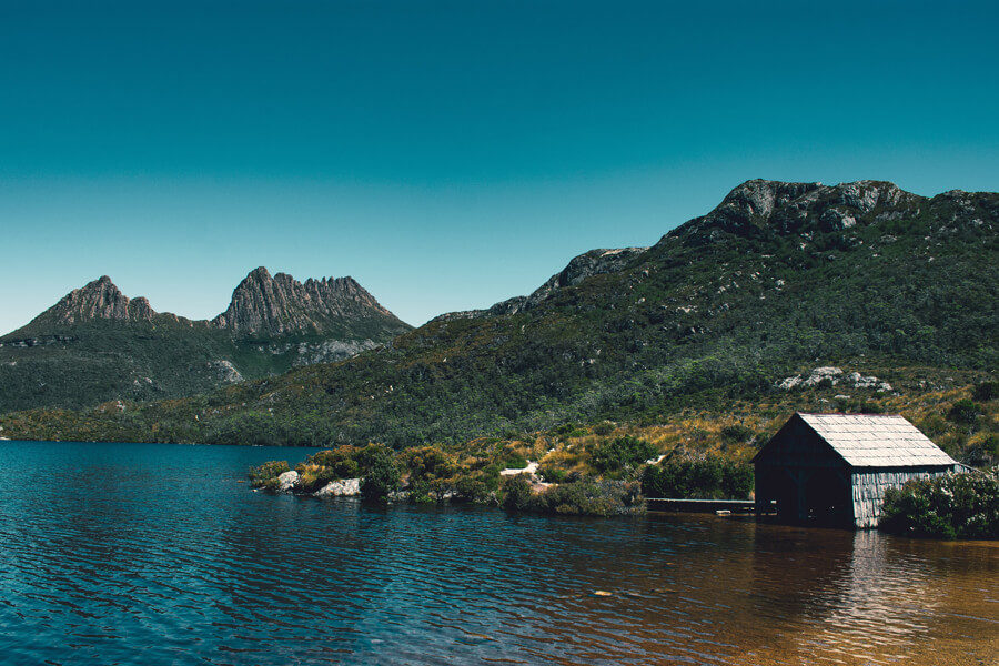 A cabin by a lake by some rocky hills