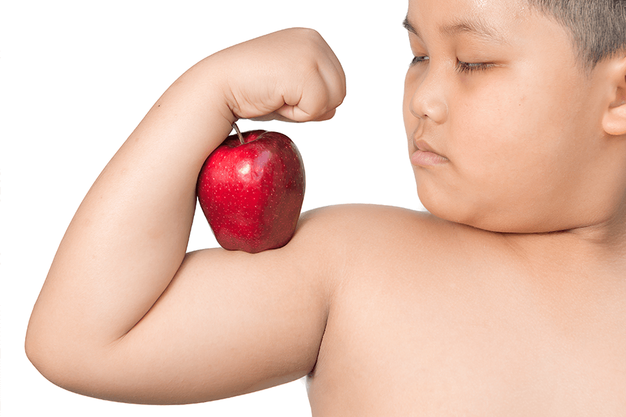Chubby child flexing his arm while holding an apple