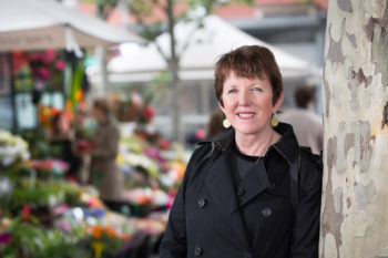 Distinguished Professor Billie Giles-Corti near a colourful flower stall.