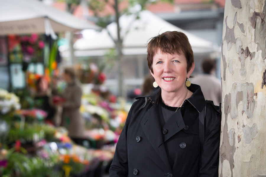 Distinguished Professor Billie Giles-Corti near a colourful flower stall.