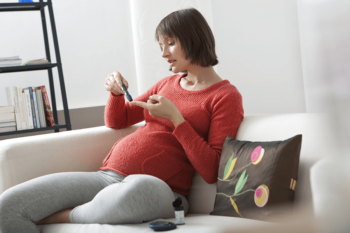 Pregnant woman checking her glucose level at home