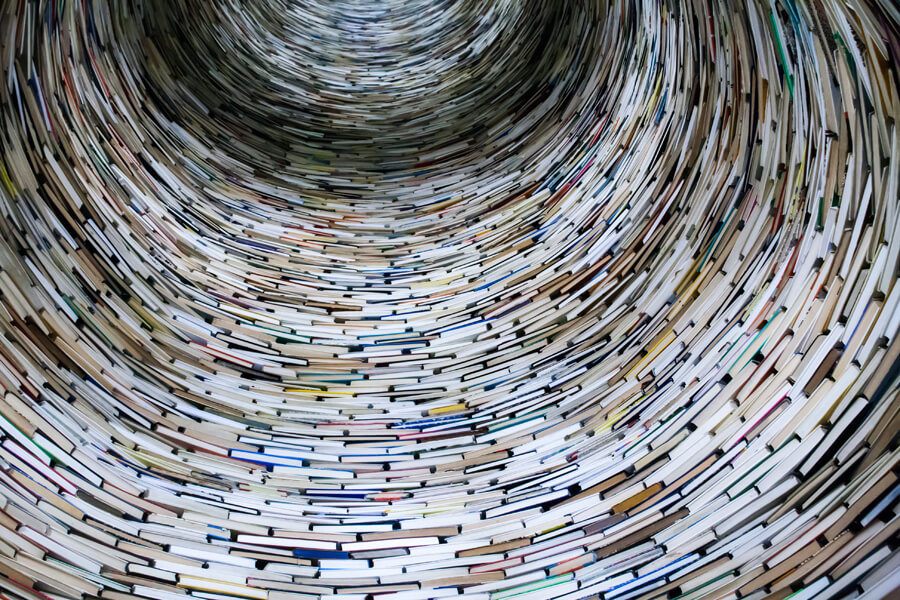 Looking up a huge vertical tunnel constructed entirely of rings of stacked books