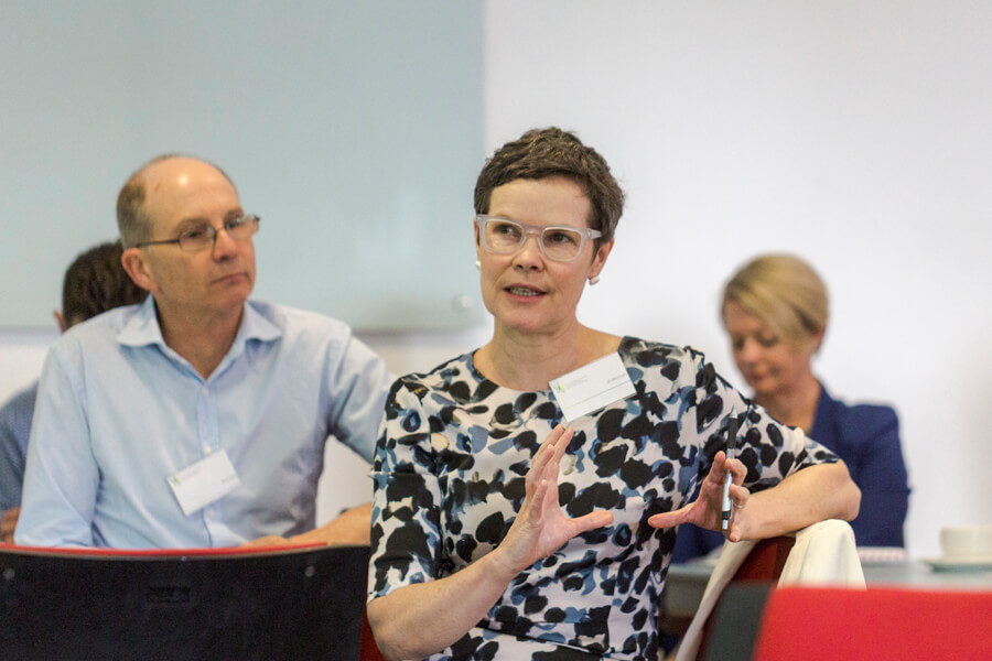 Dr Jo Mitchell speaking while sitting among participants in a workshop.