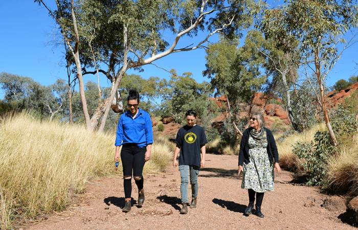 3 women walk along a track in the Australian outback