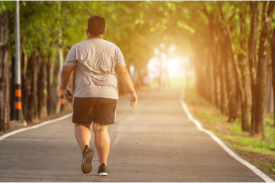 A large man exercises by walking along a road