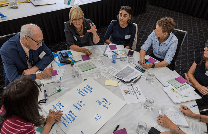 A round table covered in papers at a workshop as participants work together