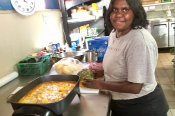 Sandra Wilson Amata smiling while cooking in a store takeaway