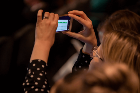 An event participant takes a photo on her mobile phone of the proceedings