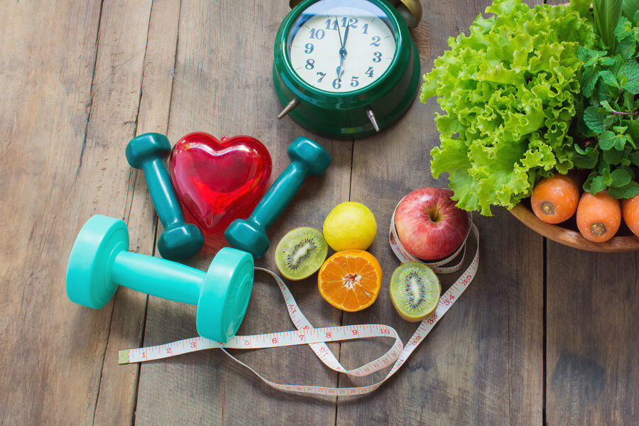 Weights, measuring tape, a clock and healthy food