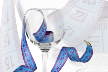 A wine glass surrounded by measuring tapes