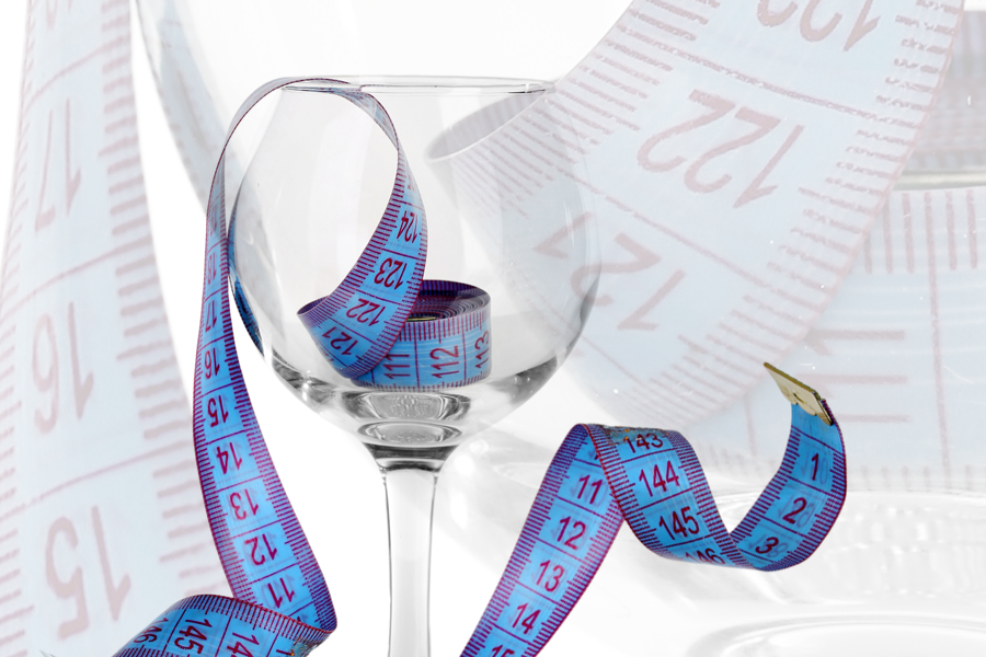 A wine glass surrounded by measuring tapes