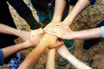 A circle of people stack their hands together in the centre