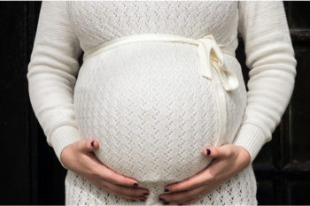 A heavily pregnant woman holds her tummy