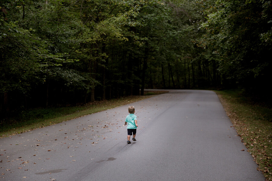 A small child running along a path among trees