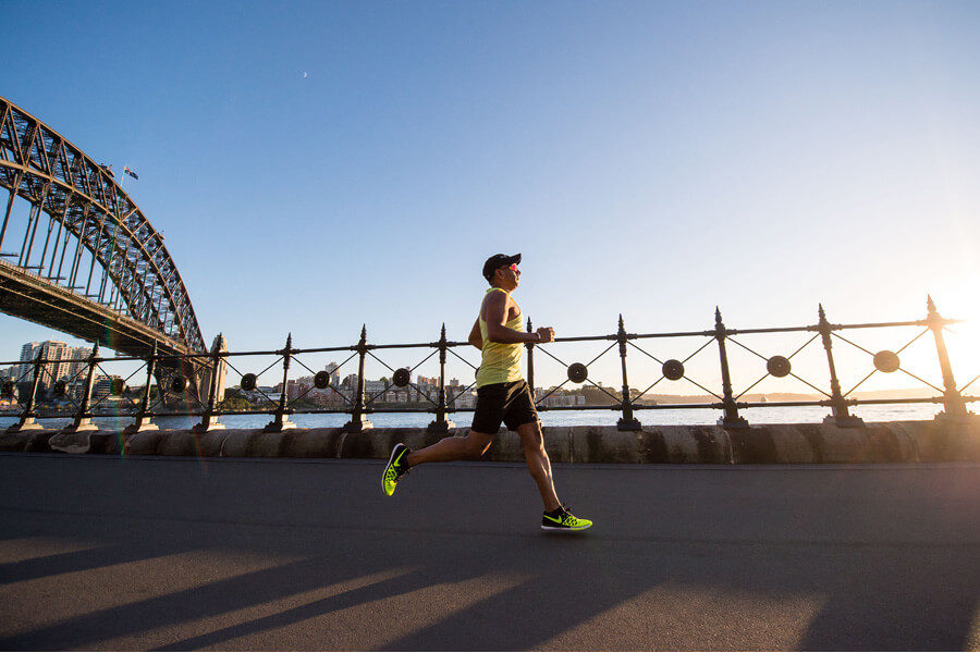 A jogger passes the Sydney Harbour Bridge on a sunny morning
