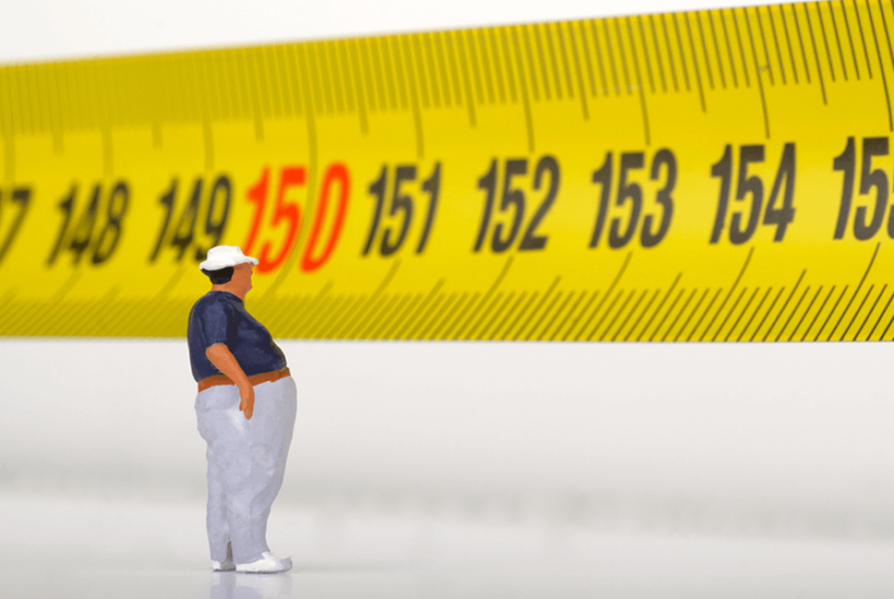 Overweight figurine standing against an oversized tape measure