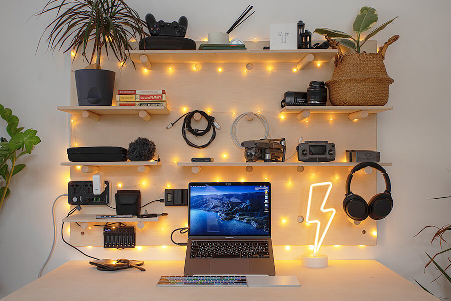 Laptop by some shelving laden with various tech equipment like cameras, headphones and cables. Photo by vadim kaipov on Unsplash https://unsplash.com/photos/f6jkAE1ZWuY