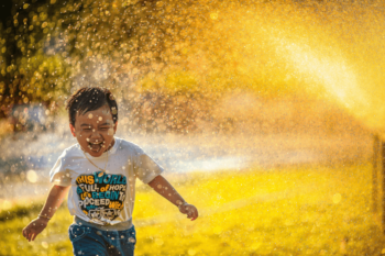 happy child running under sprinkler