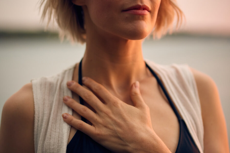 A woman with a hand on her chest. Photo by Darius Bashar on Unsplash
