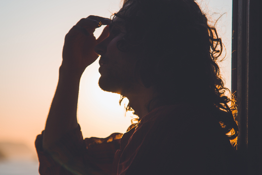 Man clutching his head as the sun sets behind him. Photo by Matteo Vistocco on Unsplash