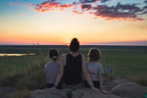 A woman and two children watch the sunset over Kakadu NT, Australia. Photo by Tim Davies on Unsplash