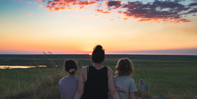 A woman and two children watch the sunset over Kakadu NT, Australia. Photo by Tim Davies on Unsplash