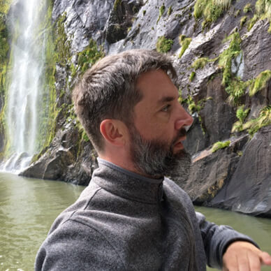 Profile shot of Patrick Harris by a waterfall