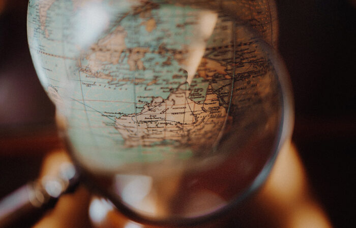 Using a magnifying glass to look at Australia on a globe