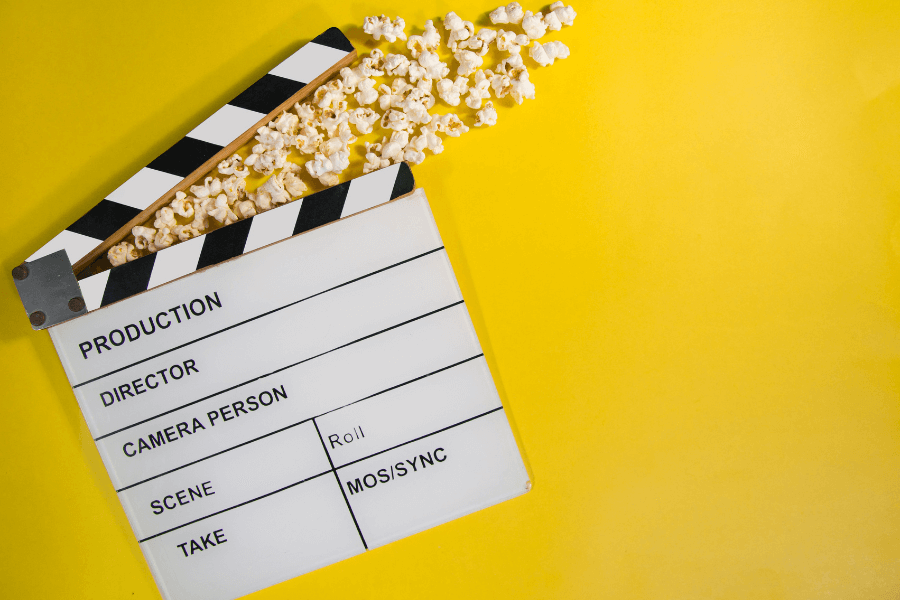 Clapperboard on yellow background with popcorn