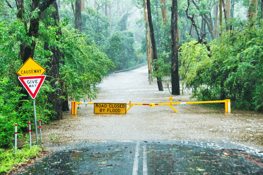Flooded road with warning sign 'road closed by flood'.