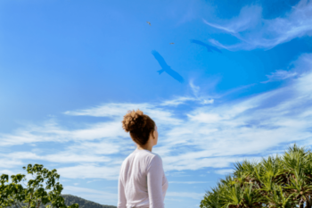 Woman looking to blue sky with clouds and birds