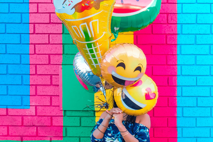 Woman holding balloons with emoji faces
