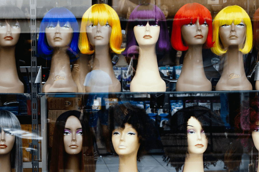 Manequin heads with different coloured wigs in a shop window