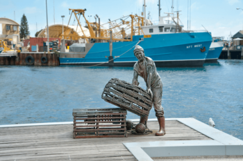 Fisherman statue at Fremantle fishing wharf with water and boats in background
